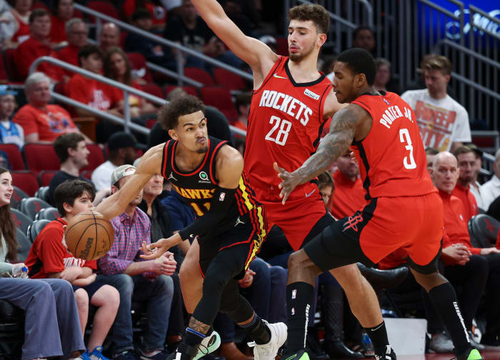 Hawks guard Trae Young attempts to pass the ball around Rockets defenders.
